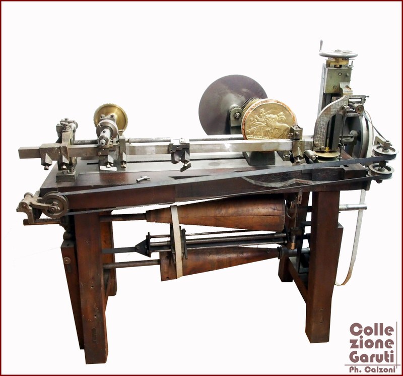 Tornio a Pantografo. Macchinario in ghisa e legno impiegato nella coniazione di monete. Nell'ambito dell'oreficeria utilizzato principalmente per realizzare medaglie di vario tipo, esemplare datato alla metà XIX secolo e prodotto in Francia.